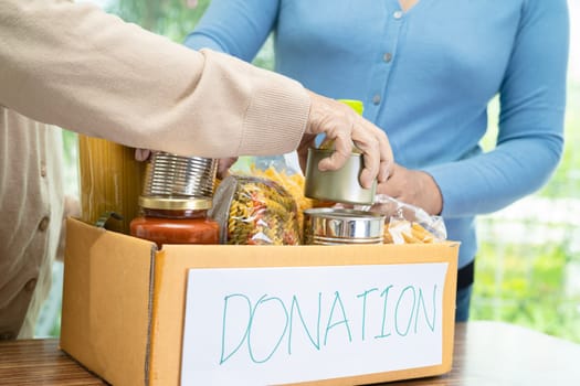 Volunteers putting various dry food in donation box for help people.