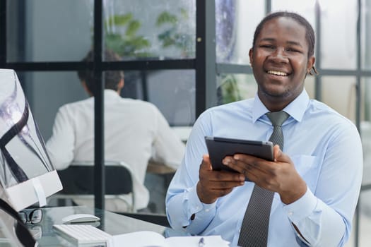 a man at a workplace at a table in front of a computer uses a tablet at office