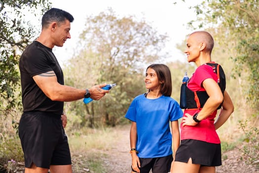 family resting and drinking during sports in nature, concept of family outdoor sport and healthy lifestyle