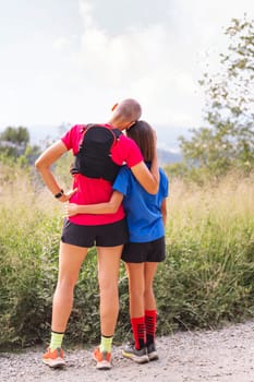 rear view of a woman with her daughter looking at the landscape after doing sports in the countryside, concept of active lifestyle and sport with kids in the nature, copy space for text