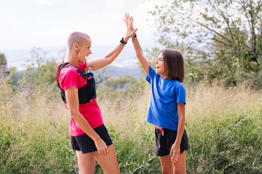 mother and daughter high five after doing sports in the countryside, concept of active lifestyle and sport with kids in the nature