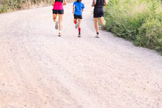 unrecognizable sporty family running in the countryside, concept of sport in nature with kids and healthy lifestyle, copy space for text