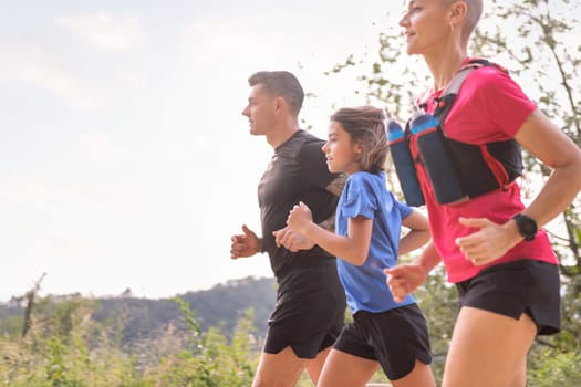 girl practicing trail running with mom and dad in the countryside, concept of sport in nature with kids and healthy lifestyle, copy space for text