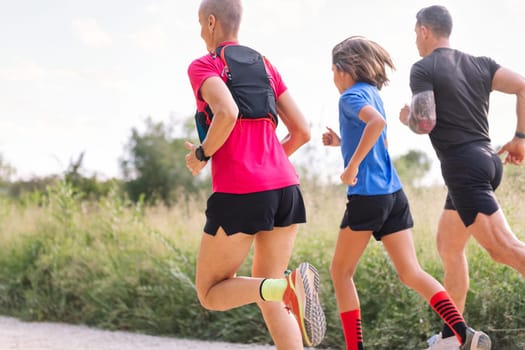 rear view of an unrecognizable sporty family running in the countryside, concept of sport in nature with kids and healthy lifestyle, copy space for text