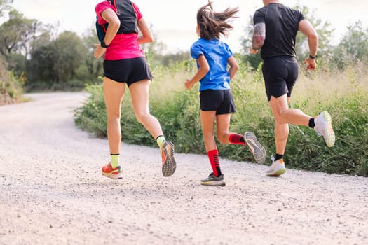 rear view of an unrecognizable sporty family running in the countryside, concept of sport in nature with kids and healthy lifestyle, copy space for text