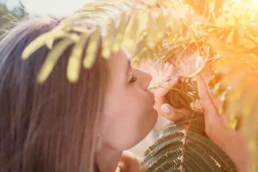 Beauty portrait of young woman closeup. Young girl smelling Chinese acacia pink blossoming flowers. Portrait of young woman in blooming spring, summer garden. Romantic vibe. Female and nature.