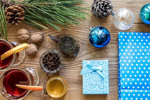 Hot mulled wine with spices on wooden background. Christmas tree branches, gifts and cones. Flat lay, copy space, top view. Holidays.