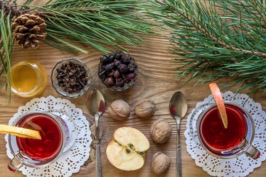 Two glass of mulled wine with cinnamon sticks, slice of oranges and apple, star anise on a wooden table. Top view. Still life. Copy space. Flat lay. Christmas hot drink