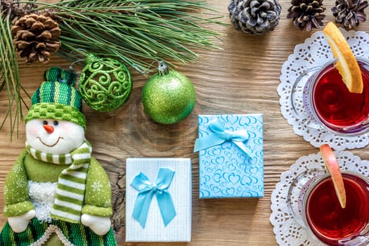 Hot mulled wine with spices on wooden background. Christmas tree branches, gifts and cones. Flat lay, copy space, top view. Holidays.