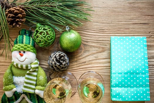 New Year's holiday with spruce branches and with a pair of wine glasses of champagne on wooden background. Flat lay, top view, copy space