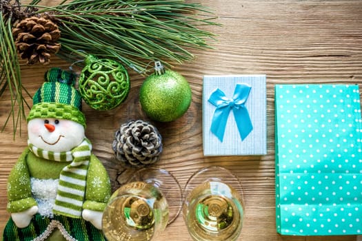 New Year's holiday with spruce branches and with a pair of wine glasses of champagne on wooden background. Flat lay, top view, copy space