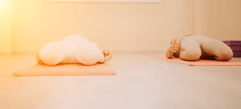 Group of young womans fitness instructor in Sportswear Leggings and Tops, stretching in the gym before pilates, on a yoga mat near the large window on a sunny day, female fitness yoga routine concept.