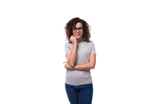 young cute pretty brunette curly caucasian lady in glasses dressed in casual jeans and t-shirt with printable mockup isolated on white background.