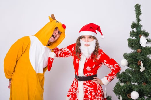 Happy young woman in santa claus hat and man in carnival costume of deer. Fun, holiday, joke and christmas concept.