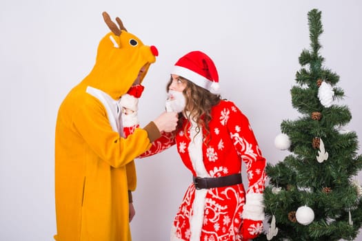 Happy young woman in santa claus hat and man in carnival costume of deer. Fun, holiday, joke and christmas concept.