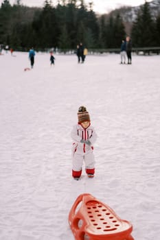 Little girl stands on the snow holding a rope in her hand. High quality photo