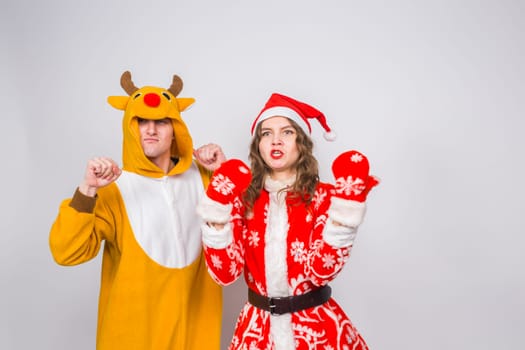 Happy young woman in santa claus hat and man in carnival costume of deer. Fun, holiday, joke and christmas concept.