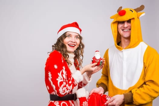 Happy young woman in santa claus hat and man in carnival costume of deer. Fun, holiday, joke and christmas concept.