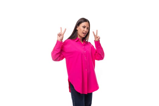 stylish charming young brunette in a bright pink oversized shirt on a white background with copy space.