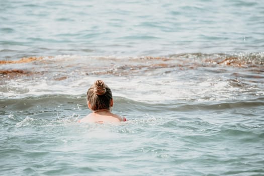 Young woman in red bikini on Beach. Girl lying on pebble beach and enjoying sun. Happy lady in bathing suit chilling and sunbathing by turquoise sea ocean on hot summer day. Close up. Back view