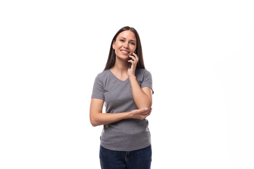 young caucasian woman with dark hair dressed in a casual gray t-shirt chatting on the phone.