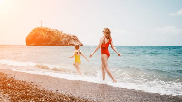 Happy loving family mother and daughter having fun together on the beach. Mum playing with her kid in holiday vacation next to the ocean - Family lifestyle and love concept.