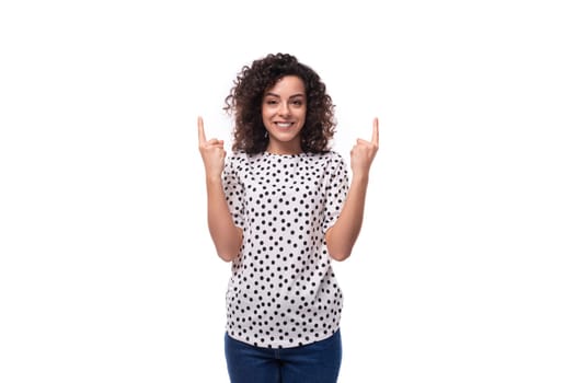 young dark-haired caucasian woman dressed in a blouse points with her hands space for advertising.