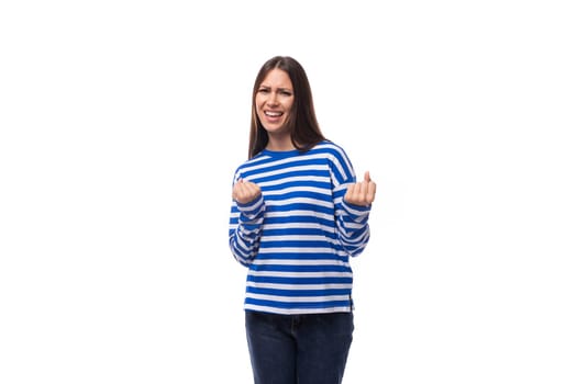 young confident european brunette woman dressed in striped blue clothes on a white studio background.