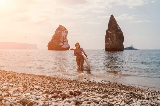 Close up shot of beautiful young caucasian woman with black hair and freckles looking at camera and smiling. Cute woman portrait in a pink bikini posing on a volcanic rock high above the sea