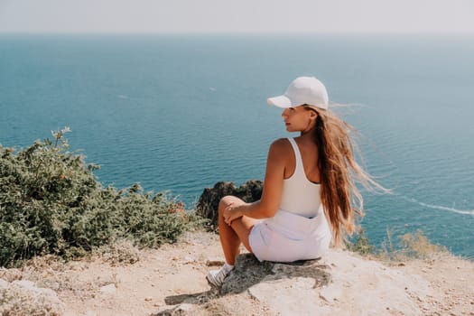 Woman travel sea. Young Happy woman in a long red dress posing on a beach near the sea on background of volcanic rocks, like in Iceland, sharing travel adventure journey