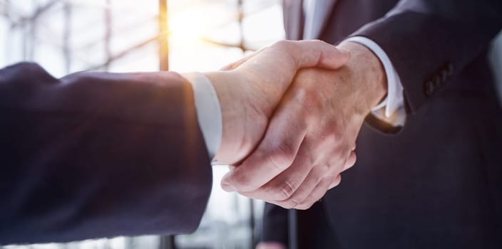 Two business people shaking hands in front of their colleagues