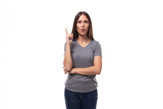 young pretty brunette woman in a gray corporate color t-shirt on a white background with copy space.