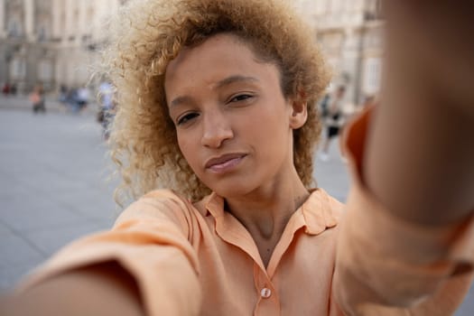Latin young woman enjoying taking selfie with smartphone while visiting in Madrid city.