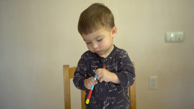 A little boy closes the cap of a felt-tip pen. Child with a felt-tip pen. 4k