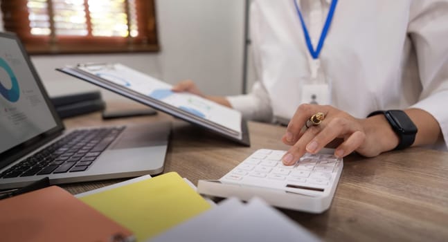 Businesswoman accountant using calculator and laptop for financial data saving in office room, Business financial, tax, accounting concept.