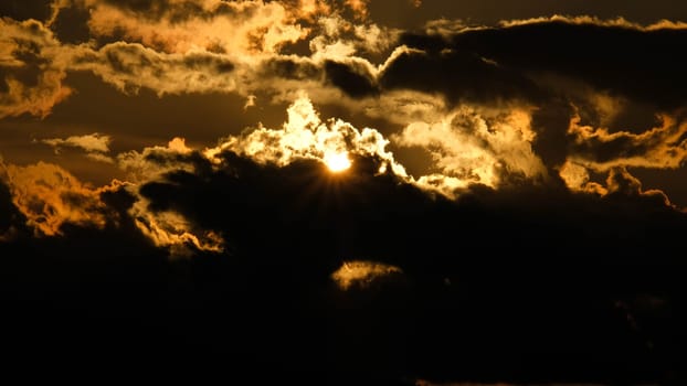 Beautiful dramatic sky with clouds at sunset or sunrise. Sunset sky at dusk in the evening with natural sky background with golden orange clouds.