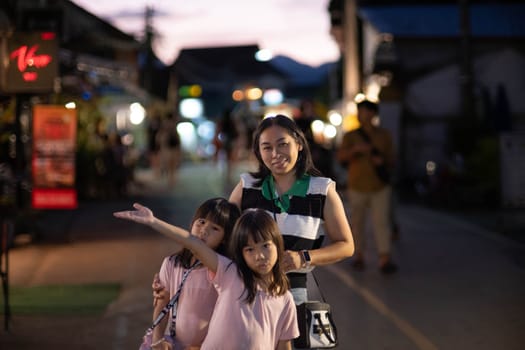 Happy family, mother and her children pose for the camera at Pai Night Walking Street, Mae Hong Son, Thailand