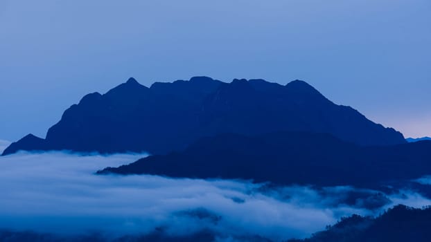 Aerial view over the mountains with sea of fog during morning sunrise in blue sky. Sea of clouds around mountain peaks at sunrise. Unseen travel in Northern Thailand.