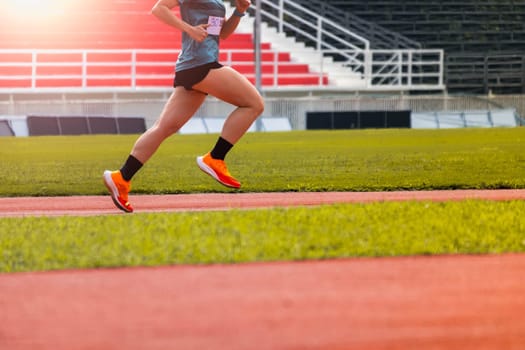 The feet of an athlete running outdoors at the racetrack. Fit young man is running on the race track. Male runner in sportswear running on stadium track with red coating outdoors.