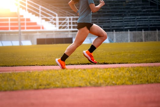 The feet of an athlete running outdoors at the racetrack. Fit young man is running on the race track. Male runner in sportswear running on stadium track with red coating outdoors.