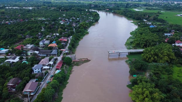 Aerial view of a damaged road bridge over a river after floodwaters washed away the asphalt. Broken bridge after flash floods in the rainy season.