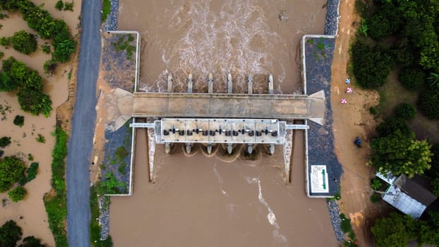 Aerial view of water released from the drainage channel of the concrete dam is a way of overflowing water in the rainy season. Top view of turbid brown forest water flows from a dam in Thailand.