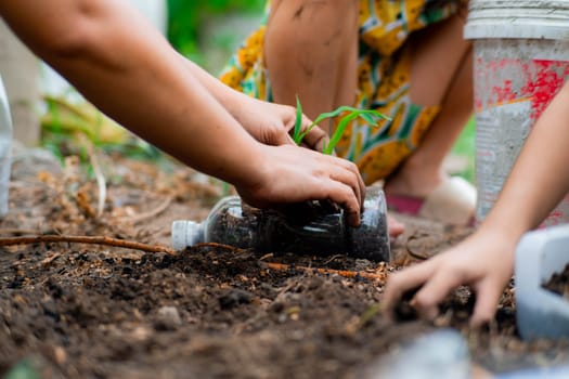 Little girl and mom grow plants in pots from recycled water bottles in the backyard. Recycle water bottle pot, gardening activities for children. Recycling of plastic waste