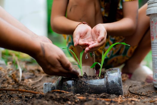 Little girl and mom grow plants in pots from recycled water bottles in the backyard. Recycle water bottle pot, gardening activities for children. Recycling of plastic waste