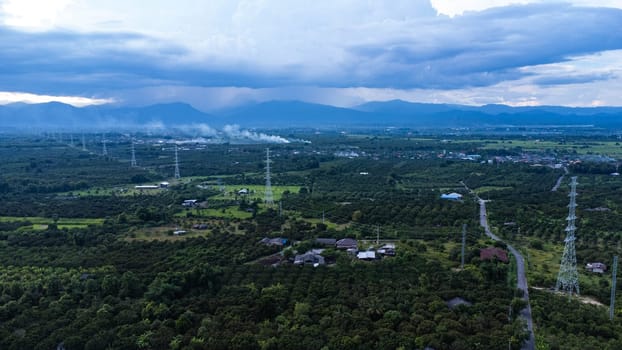 High voltage electric pylon for distributing electricity from power stations to customers through the national electricity grid. High voltage grid tower with wire cable at tree forest. Power and energy concept. Landscape.