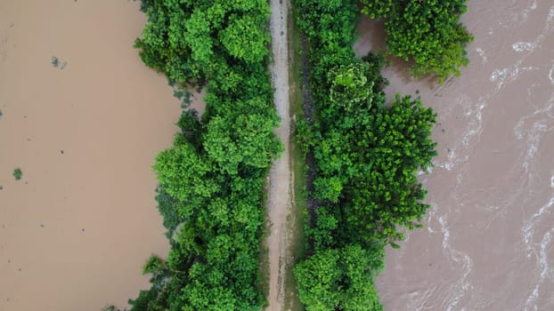 Aerial view of the area affected by rainy season flooding. Top view of a flowing river after heavy rain and flooding of agricultural land in rural northern Thailand.