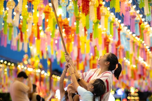 Asian families make wishes and hang lanterns during The Hundred Thousand Lantern Festival or Yi Peng Festival in northern Thailand.