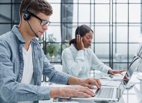 man using a headset and computer in a modern office