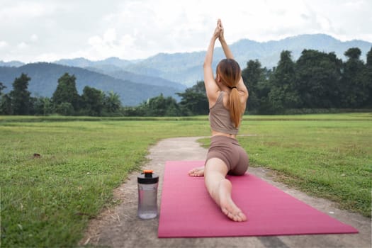 Asian female in sportswear practicing yoga in the park.