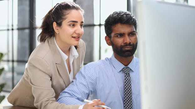 colleagues discussing project while working with laptop in office indoors